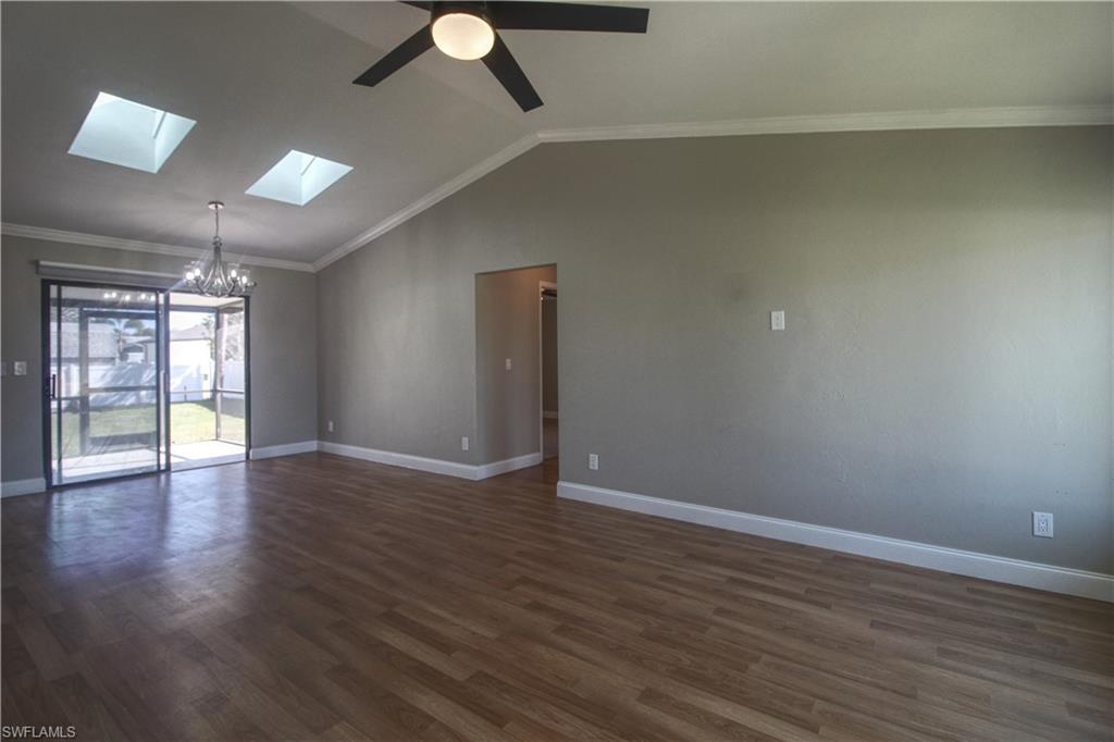 18257 Sycamore Road Fort Myers, FL 33967 - Photo 1 of 19 Main area with lofted ceiling with skylight, crown molding, dark wood-type flooring, and ceiling fan with notable chandelier