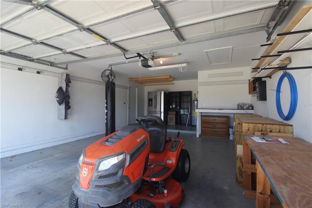 18257 Sycamore Road Fort Myers, FL 33967 - Photo 11 of 19 Garage featuring a workshop area, stainless steel fridge, strapped water heater, and a garage door opener