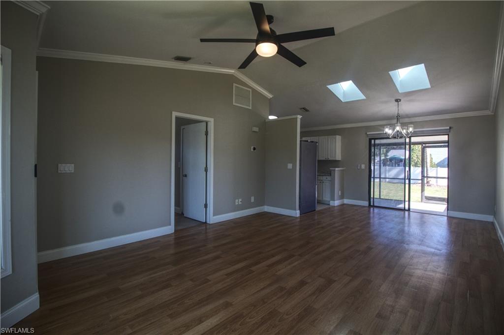 18257 Sycamore Road Fort Myers, FL 33967 - Photo 2 of 19 Unfurnished living room featuring lofted ceiling with skylight, crown molding, dark hardwood / wood-style floors, and ceiling fan with notable chandelier