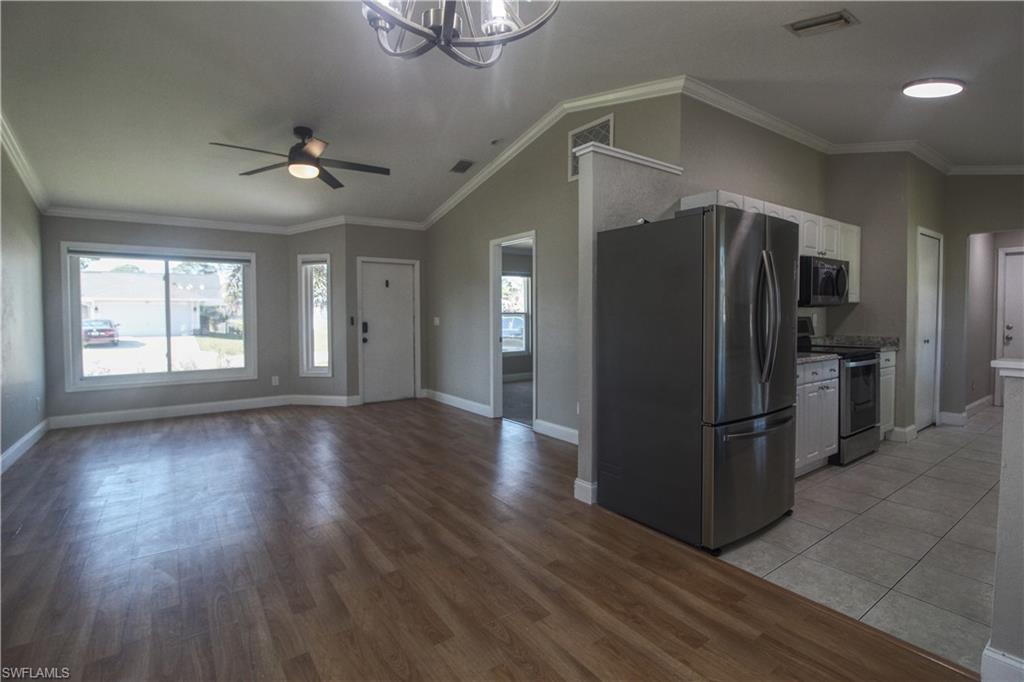 18257 Sycamore Road Fort Myers, FL 33967 - Photo 3 of 19 Kitchen featuring stainless steel appliances, crown molding, vaulted ceiling, white cabinets, and ceiling fan with notable chandelier