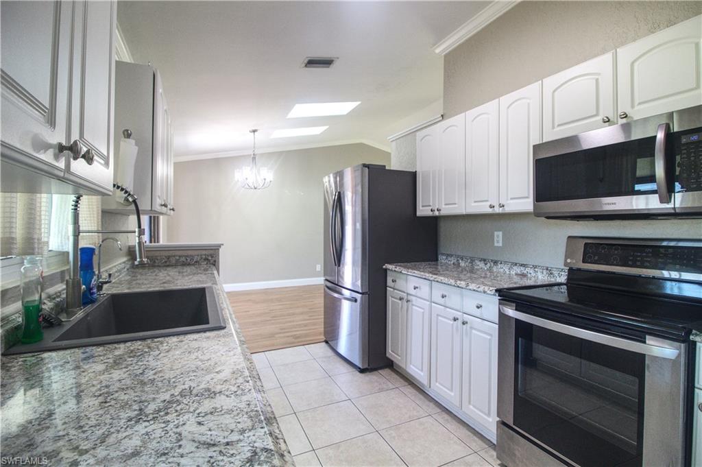 18257 Sycamore Road Fort Myers, FL 33967 - Photo 5 of 19 Kitchen with light stone countertops, appliances with stainless steel finishes, crown molding, sink, and white cabinets