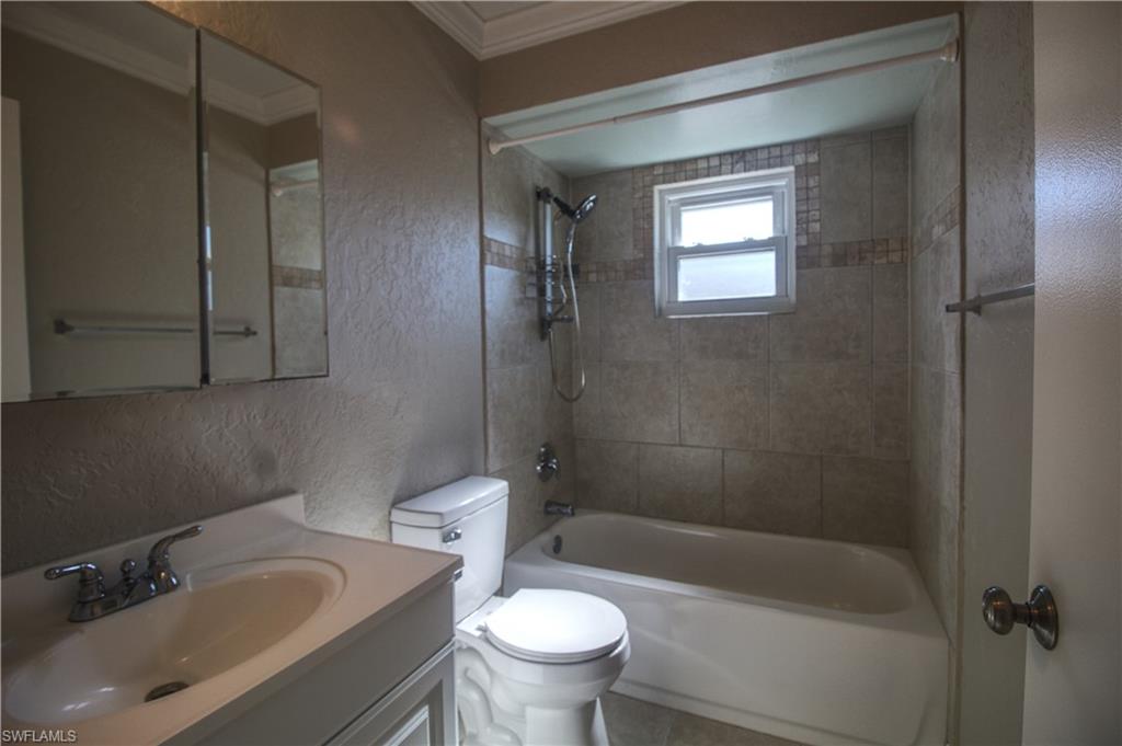 18257 Sycamore Road Fort Myers, FL 33967 - Photo 10 of 19 Guest bathroom with tiled shower / bath combo, tile patterned floors, toilet, vanity, and ornamental molding