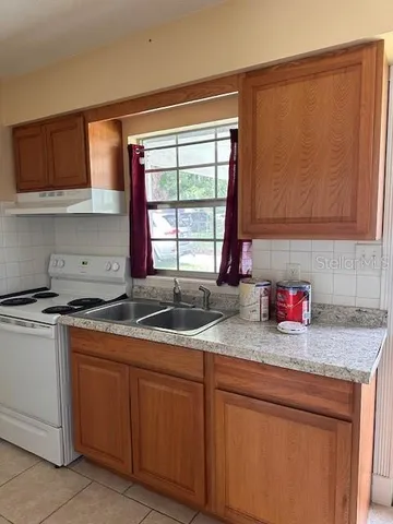 a kitchen with granite countertop stainless steel appliances a sink window and cabinets