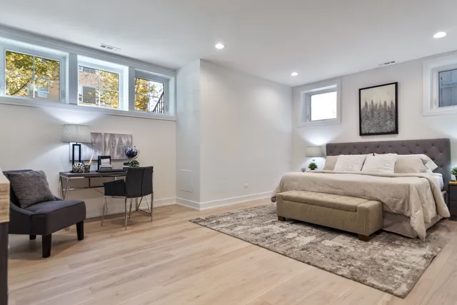 a spacious bedroom with a bed a couch and potted plant on the wooden floor