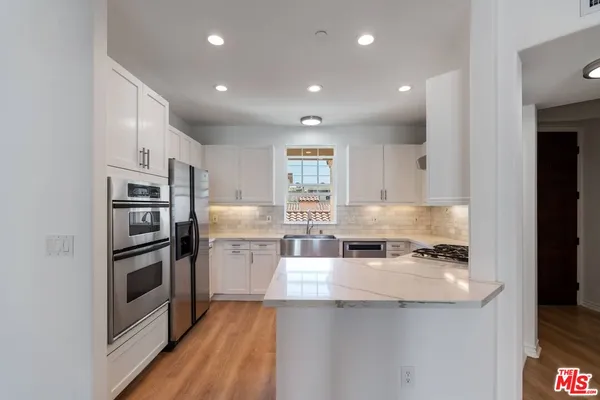 a kitchen with white cabinets appliances and a sink