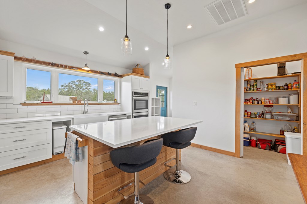456 Colt Valley Road Fredericksburg, TX 78624 - Photo 14 of 46 a kitchen with a stove a refrigerator and a dining table with wooden floor