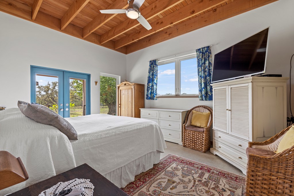 456 Colt Valley Road Fredericksburg, TX 78624 - Photo 18 of 46 a bedroom with a bed a flat screen tv and balcony view