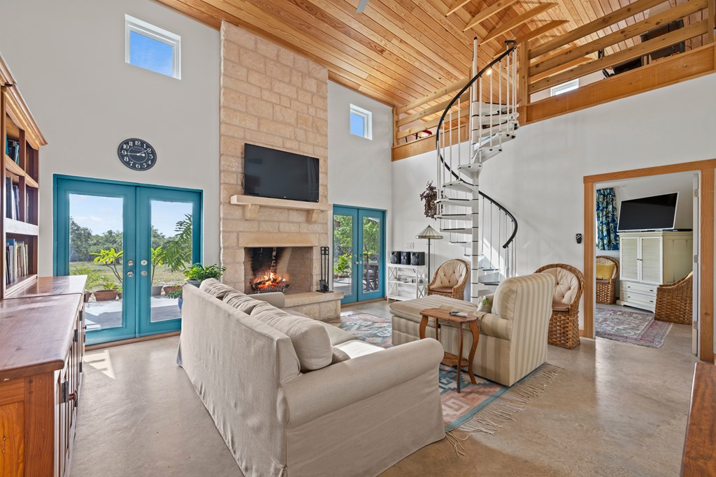 456 Colt Valley Road Fredericksburg, TX 78624 - Photo 9 of 46 a living room with furniture a fireplace and a floor to ceiling window