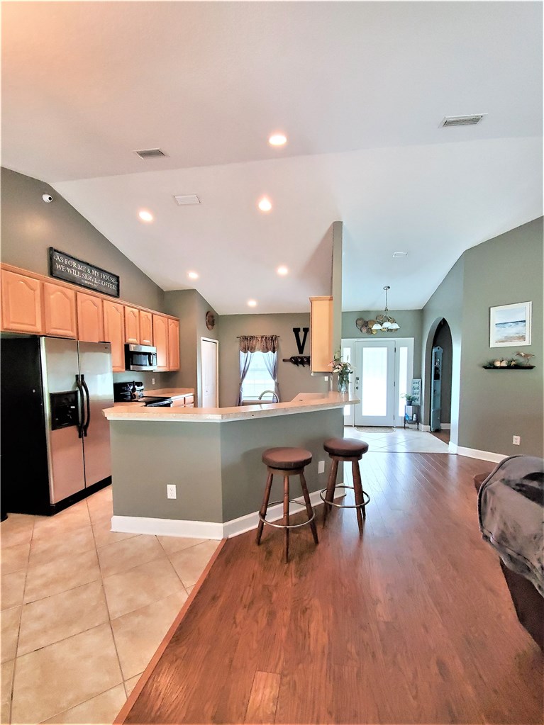 54414 Armstrong Road Callahan, FL 32011 - Photo 6 of 25 a kitchen with stainless steel appliances granite countertop a refrigerator a sink dishwasher a stove and a dining table with wooden floor