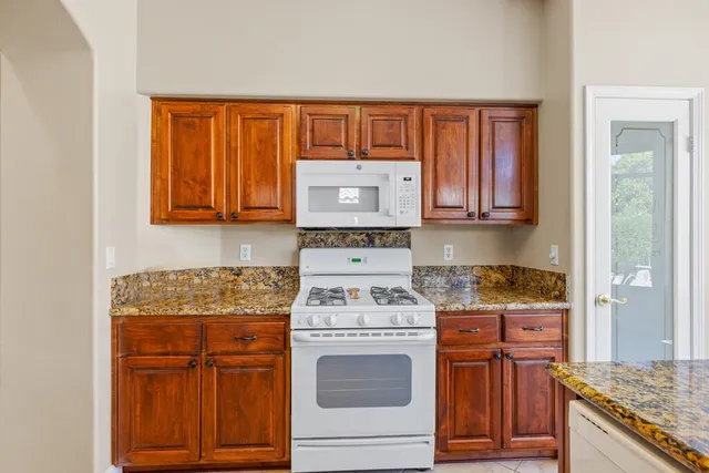 a kitchen with stainless steel appliances granite countertop wooden cabinets stove top oven and granite counter top