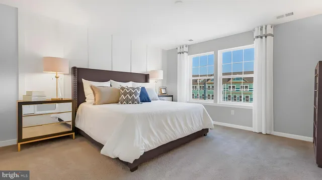 a spacious bedroom with a bed and a dresser next to a window