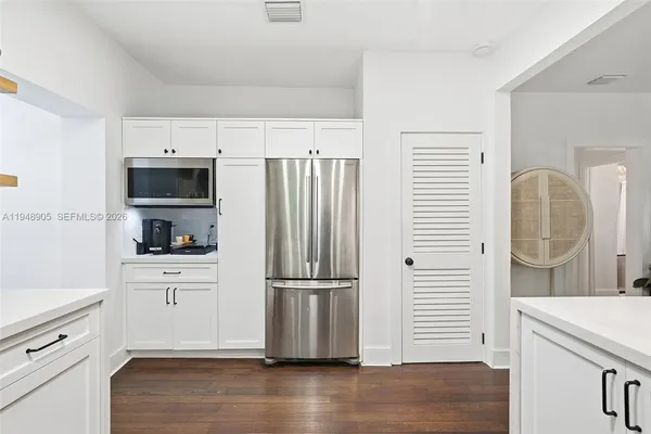 a kitchen with granite countertop a refrigerator stove and wooden floor
