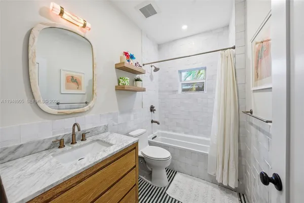 a bathroom with a granite countertop sink mirror vanity and toilet