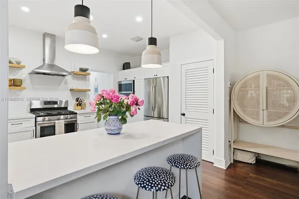 a kitchen with stainless steel appliances granite countertop a stove a sink dishwasher and a dining table with wooden floor