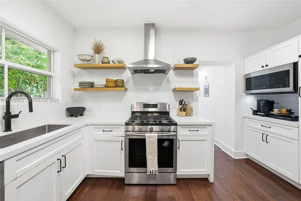 a kitchen with stainless steel appliances a stove and white cabinets