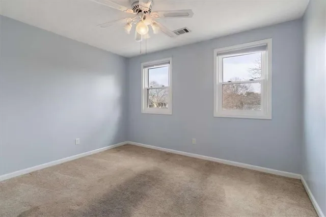 an empty room with windows and fan