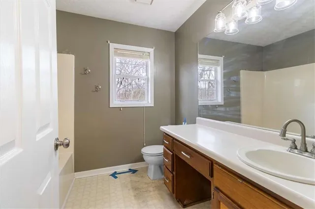 a bathroom with a sink a toilet a mirror and a window