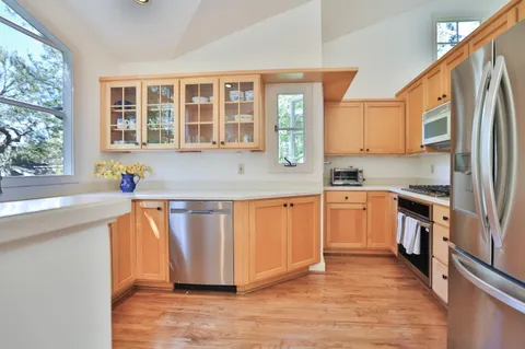 a kitchen with stainless steel appliances granite countertop a stove a sink dishwasher a refrigerator and cabinets with wooden floor