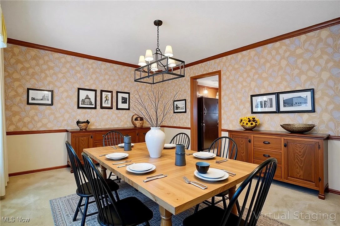 7300 Morley Road Painesville, OH 44077 - Photo 23 of 50 Dining space featuring light colored carpet, ornamental molding, wallpapered walls, a chandelier, and a wainscoted wall