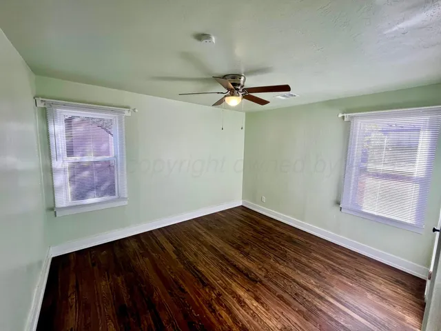 a view of an empty room with window and wooden floor