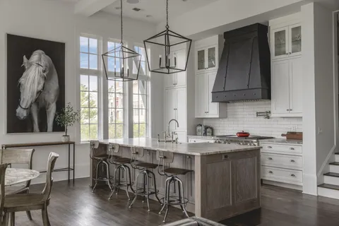 a kitchen with stainless steel appliances granite countertop a stove a refrigerator a sink a dining table and chairs with wooden floor