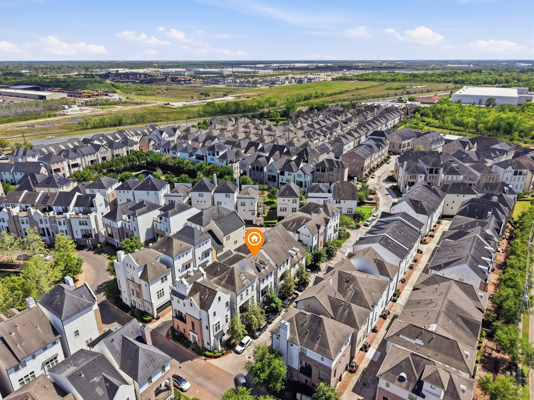 9427 London Bridge Station Houston, TX 77045 - Photo 29 of 30 This aerial view showcases a modern residential neighborhood with closely built townhouses, well-maintained roads, and greenery. The homes feature varied rooflines and are arranged in a neat, organized layout. The area appears to be spacious with easy access to surrounding amenities and open spaces.