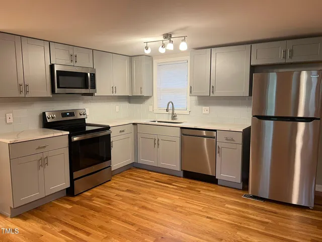 a kitchen with a sink a refrigerator and white cabinets