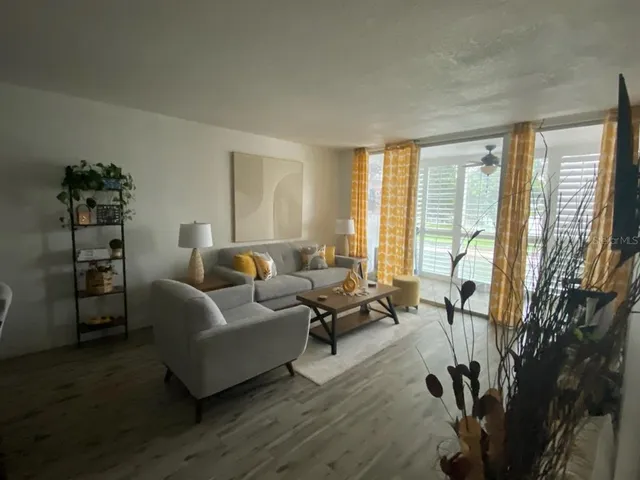 a living room with furniture a large window and wooden floor