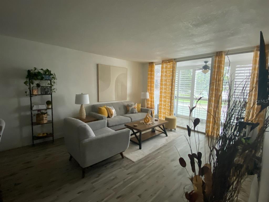 8350 Sands Point Boulevard, Unit 205E Fort Lauderdale, FL 33321 - Photo 7 of 16 a living room with furniture a large window and wooden floor