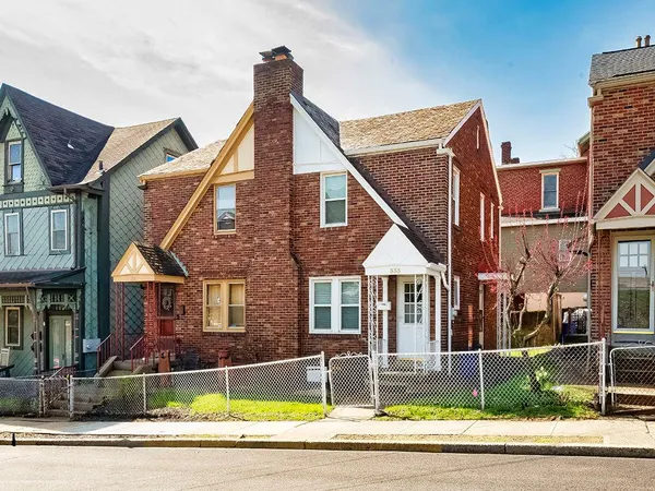 a view of a brick house with a yard lawn chairs and a fire pit
