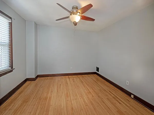 a view of a room with wooden floor and a ceiling fan