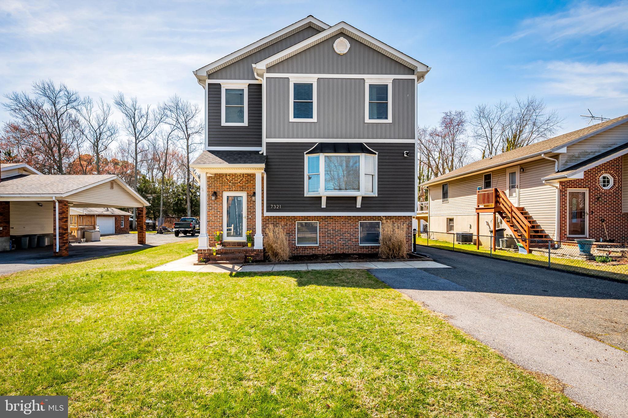 a front view of house with yard and trees in the background