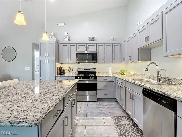 a kitchen with granite countertop a sink a counter top space appliances and cabinets