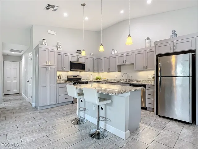 a kitchen with stainless steel appliances granite countertop a refrigerator and a stove top oven