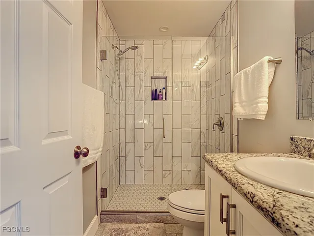 a bathroom with a granite countertop shower sink vanity mirror and toilet
