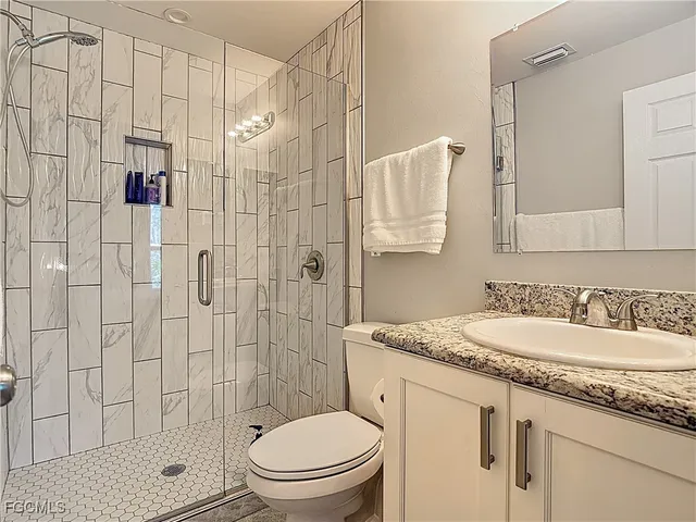 a bathroom with a granite countertop sink a toilet and shower