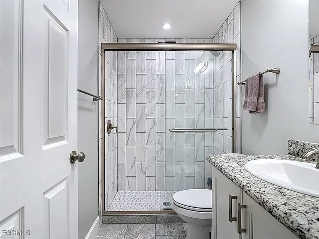 a bathroom with a granite countertop sink toilet and shower