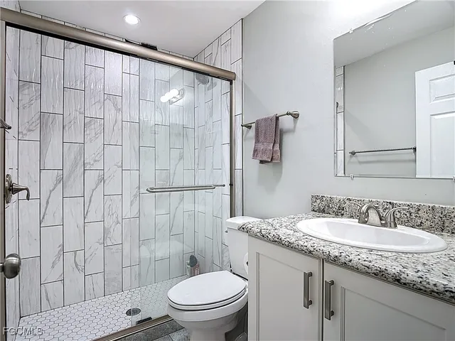 a bathroom with a granite countertop sink toilet and shower
