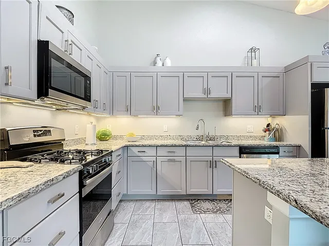 a kitchen with stainless steel appliances granite countertop a stove top oven a sink dishwasher and a microwave oven with the cabinets