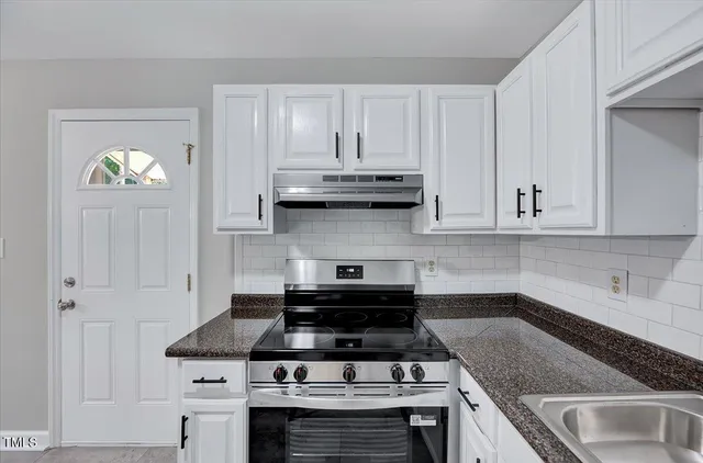 a kitchen with granite countertop white cabinets and stainless steel appliances