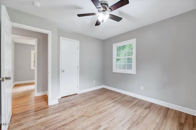a view of empty room with wooden floor and fan