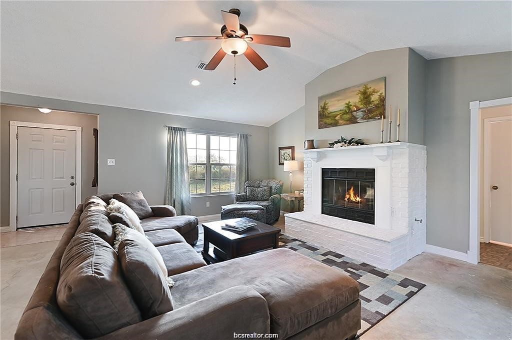 9776 Calhoun Road Bryan, TX 77808 - Photo 18 of 50 a living room with furniture a fireplace and a flat screen tv