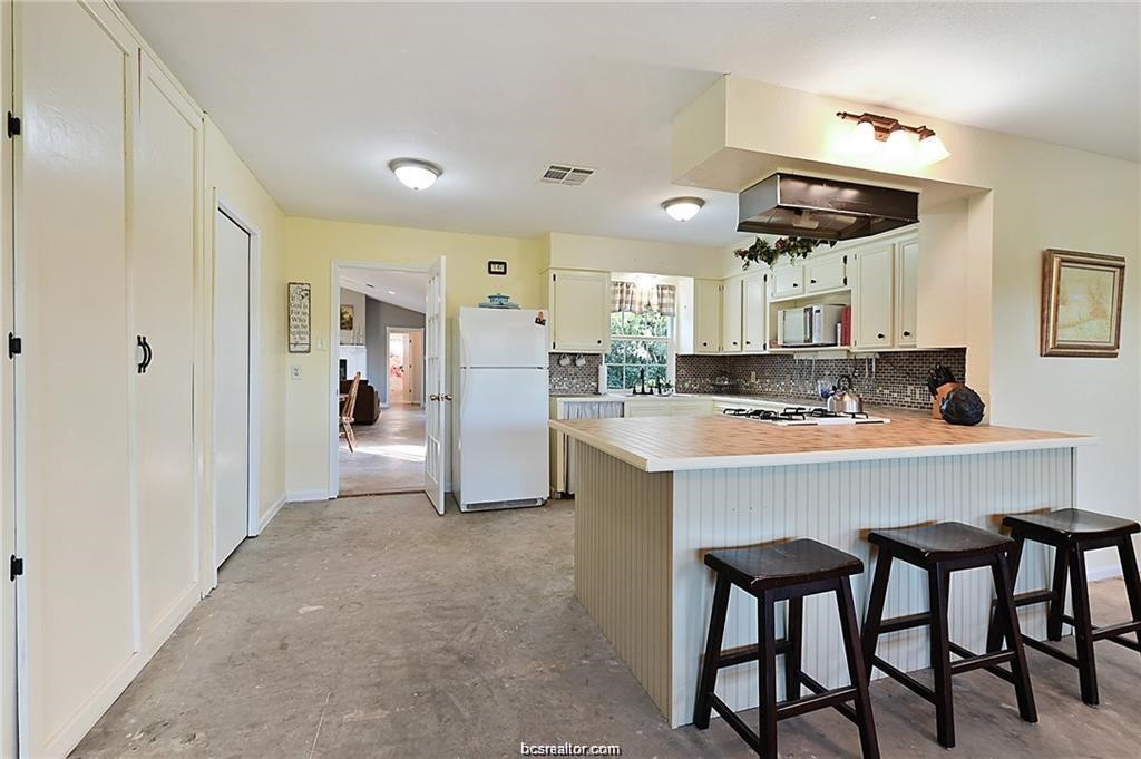 9776 Calhoun Road Bryan, TX 77808 - Photo 22 of 50 a kitchen with stainless steel appliances cabinets a dining table and chairs