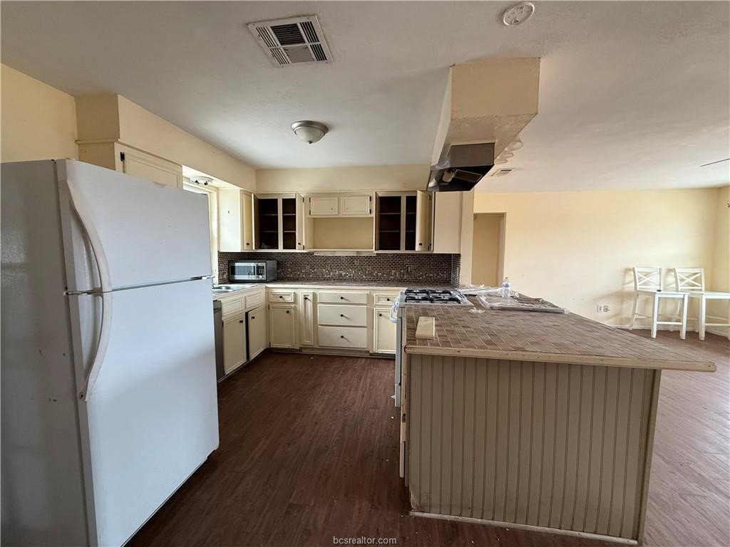 9776 Calhoun Road Bryan, TX 77808 - Photo 9 of 50 a kitchen with stainless steel appliances granite countertop a refrigerator a stove a sink dishwasher and a refrigerator with wooden floor