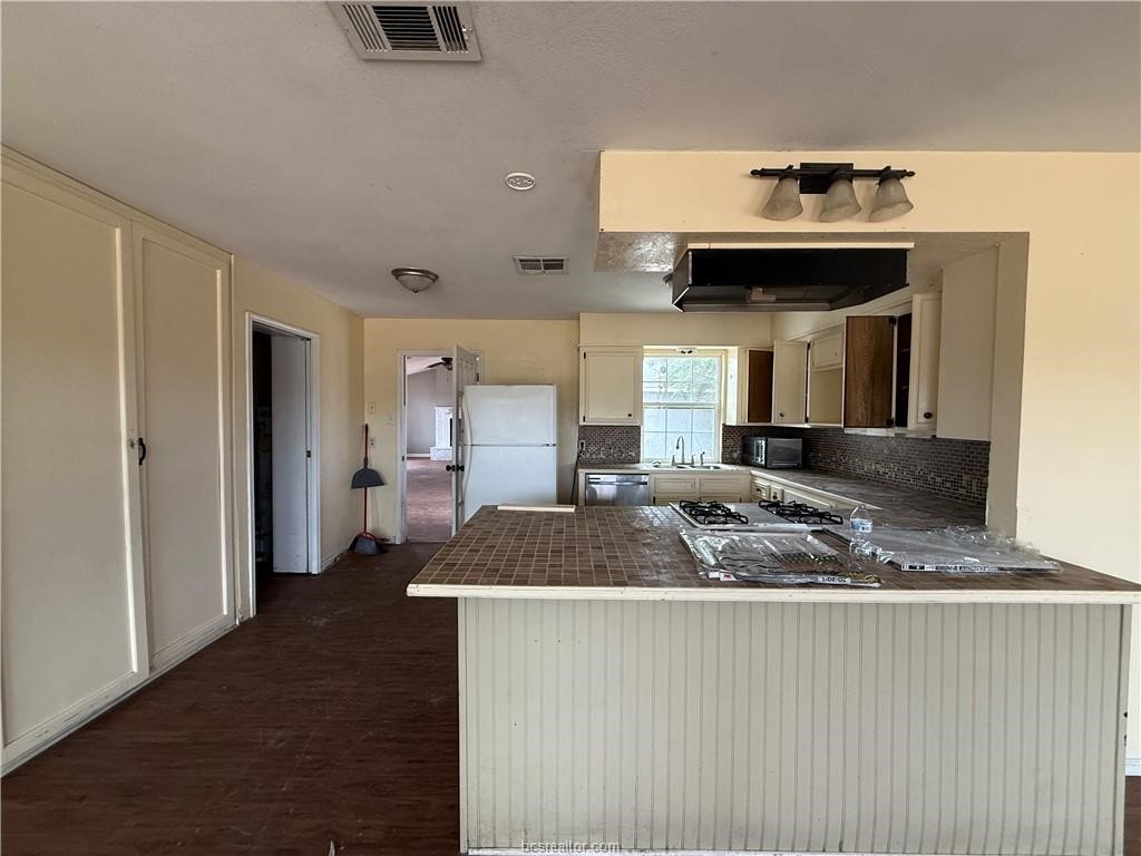 9776 Calhoun Road Bryan, TX 77808 - Photo 10 of 50 a kitchen with a sink a refrigerator and cabinets