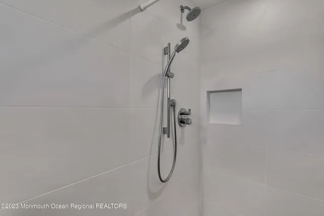 a view of a patio with table and chairs under an umbrella with barbeque grill and large trees