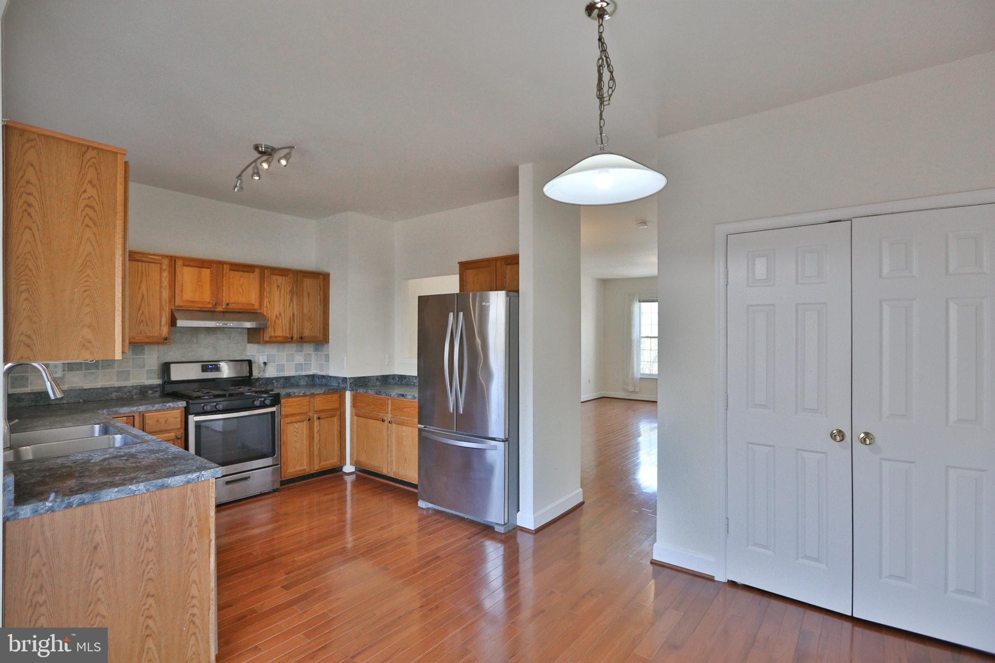 14214 Beddingfield Way Centreville, VA 20121 - Photo 17 of 19 a kitchen with stainless steel appliances granite countertop a refrigerator a stove a sink dishwasher and a stove with wooden floor