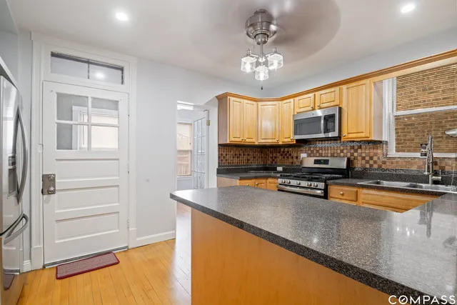 a kitchen with stainless steel appliances granite countertop a stove top oven a sink dishwasher a dining table and chairs with wooden floor