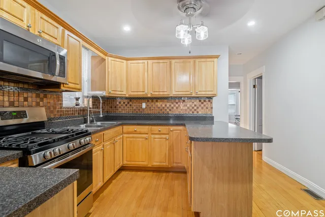a kitchen with stainless steel appliances granite countertop a stove a sink and a microwave