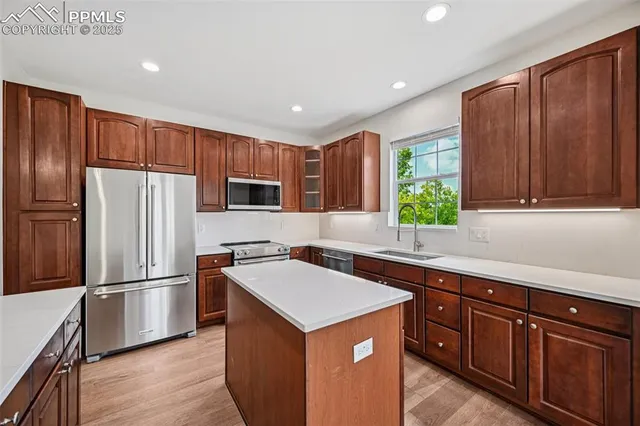 a kitchen with stainless steel appliances granite countertop a refrigerator a sink dishwasher a stove with wooden cabinets and a refrigerator